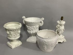 A white pottery table lamp modelled as three cherubs on a fluted and swagged circular base