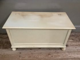 A cream painted ottoman with hinged lid, 91cm wide