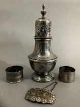 A silver plate on copper sugar sifter, two George V silver napkin rings and a George V spirit label