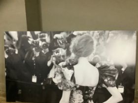 A black and white print on canvas of a woman at a premiere in a floral dress in front of press,