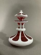 A Bohemian ruby glass scent bottle with white overlay cut with roundels having a drop stopper,