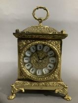 An ornate brass mantel clock with foliate moulding on paw feet with quartz movement, 23cm high