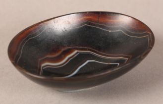 A BANDED AGATE BOWL of oval outline on foot rim, 9cm wide x 6.5cm deep x 2.75cm high (two cracks