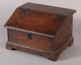 AN 18TH CENTURY OAK BOX with hinged sloping lid, with brass escutcheon on bracket feet, fitted