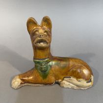 A TANG-STYLE SANCAI GLAZED POTTERY FIGURE OF A RECUMBENT DOG, 18cm wide x 14cm high (Shipping