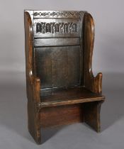 AN 18TH CENTURY STYLE OAK WINGED CHAIR, the back carved with a panel of interlocking foliate