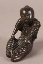 A 19TH CENTURY JAPANESE BRONZE FIGURE OF A MAN IN FLOWING ROBES, sitting, his hands on his knees,