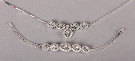 A DIAMOND SET NECKLACE AND BRACELET SUITE, c1970, each link claw set to the centre with a