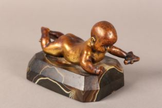 A GILDED BRONZE FIGURE OF AN INFANT lying on it's stomach, on an agate base, 14.5cm long x 9.5cm
