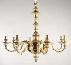 A GILT METAL EIGHT LIGHT chandelier, the central baluster stem cast with scrolls and lion masks