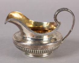 A GEORGE III SILVER CREAM JUG, London 1818 for Paul Storr, having a half reeded body and leaf capped