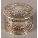 A CHINESE SILVER BOX AND COVER, cylindrical, embossed with dragons chasing the flaming pearl on a