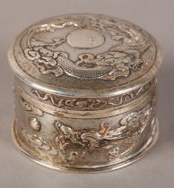 A CHINESE SILVER BOX AND COVER, cylindrical, embossed with dragons chasing the flaming pearl on a