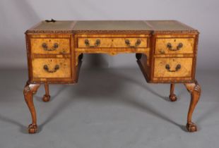 AN 18TH CENTURY-STYLE FIGURED WALNUT DESK, inverted breakfront, having three incised leather panels,