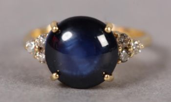 A STAR SAPPHIRE AND DIAMOND RING IN 18CT GOLD, claw set to the centre with a circular cabochon