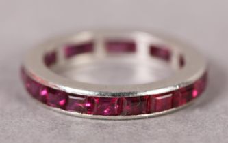 A RUBY COCKTAIL RING IN PLATINUM C1935, the calibre cut stone channel set in line, finger size K,
