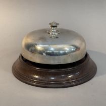 AN EARLY 20TH CENTURY SILVER PLATED AND OAK COUNTER BELL, 13cm high x 21.5cm diameter (Shipping