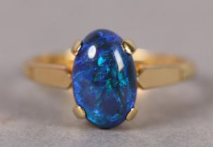A BLACK OPAL RING in 18ct gold, the single oval cabochon stone claw set over shoulders and shank,