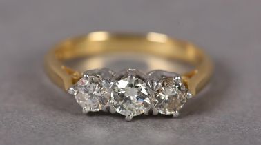 A THREE STONE DIAMOND RING in 18ct yellow and white gold, the graduated brilliant cut stones crown