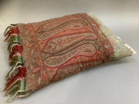 A 19th century paisley shawl in reds, gressn and yellows with fringing together with a matching