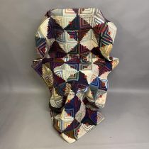 An early 20th century log cabin quilt, incorporating a wide variety of printed fabrics in purples,