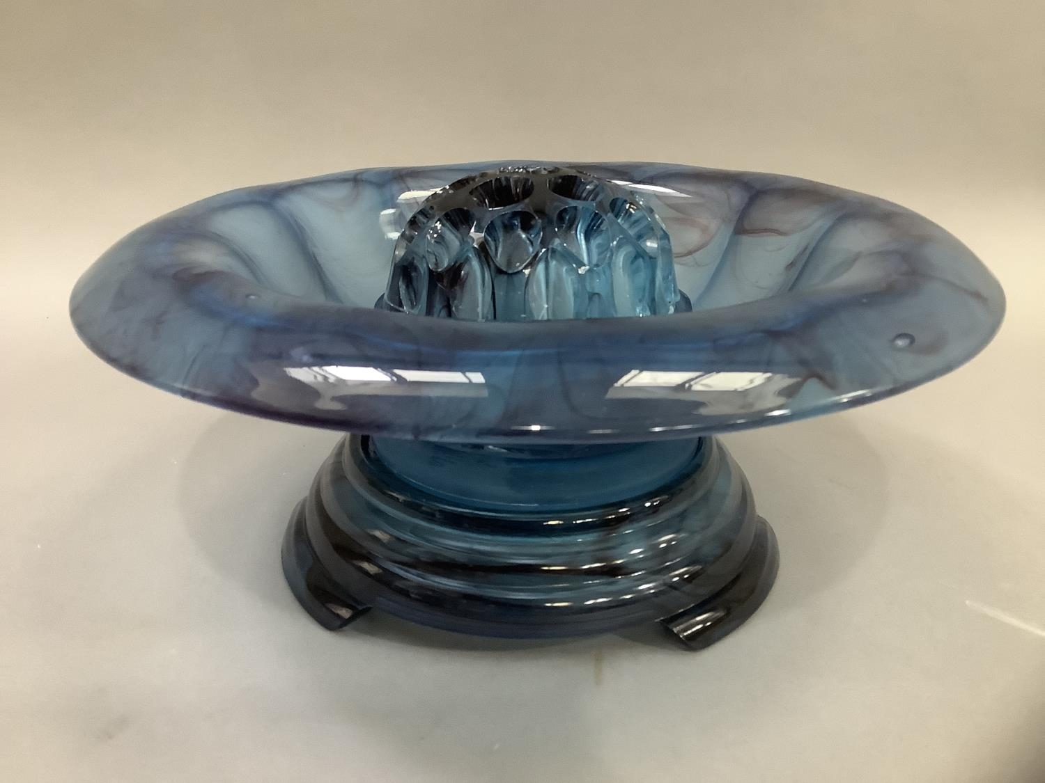 An Art Deco blue cloud glass bowl with broad everted rim on stand, with central posy, 35cm wide