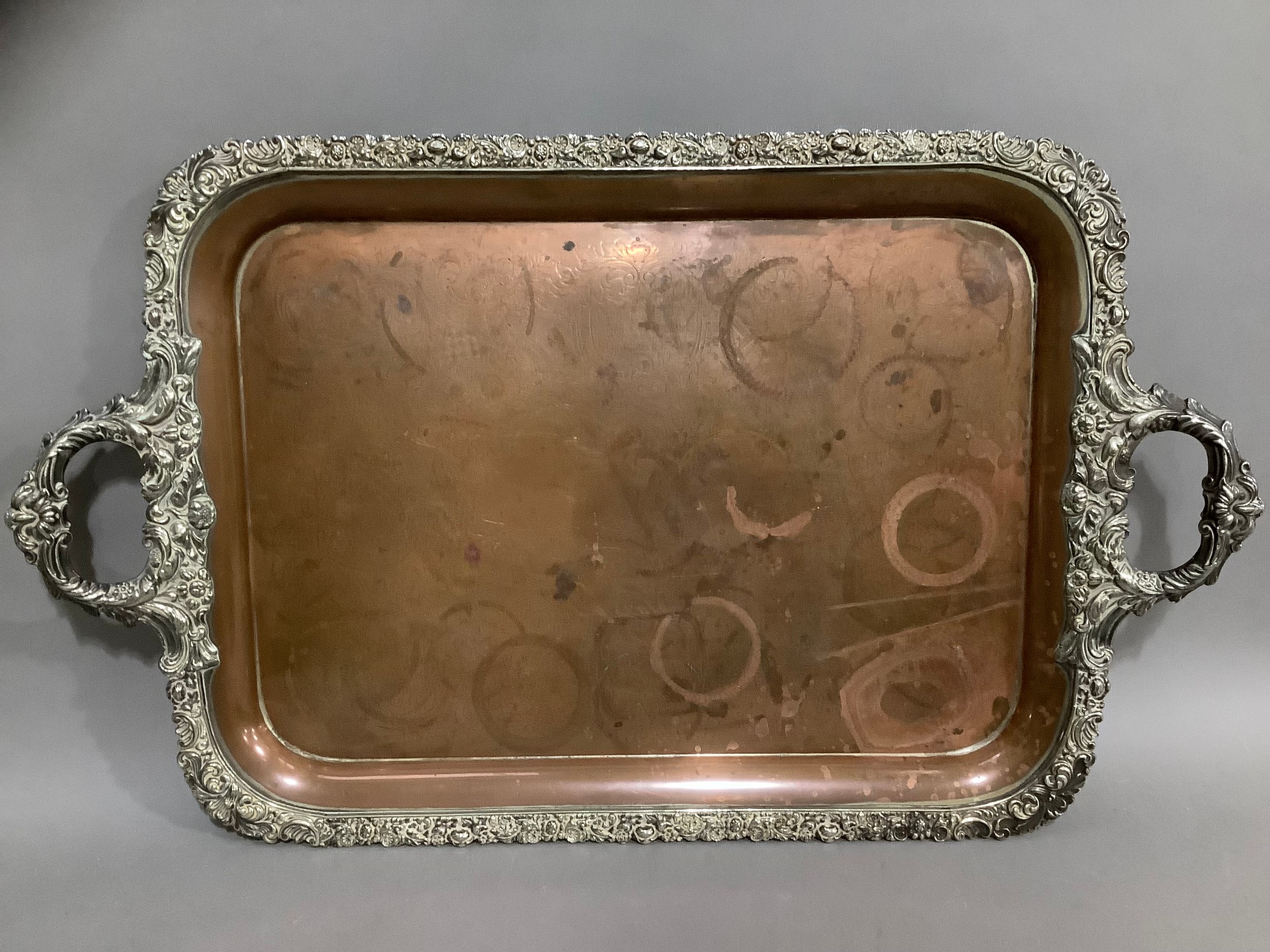 A Victorian plated on copper two handled tray, the rim cast with fruiting leafage and flowerheads,