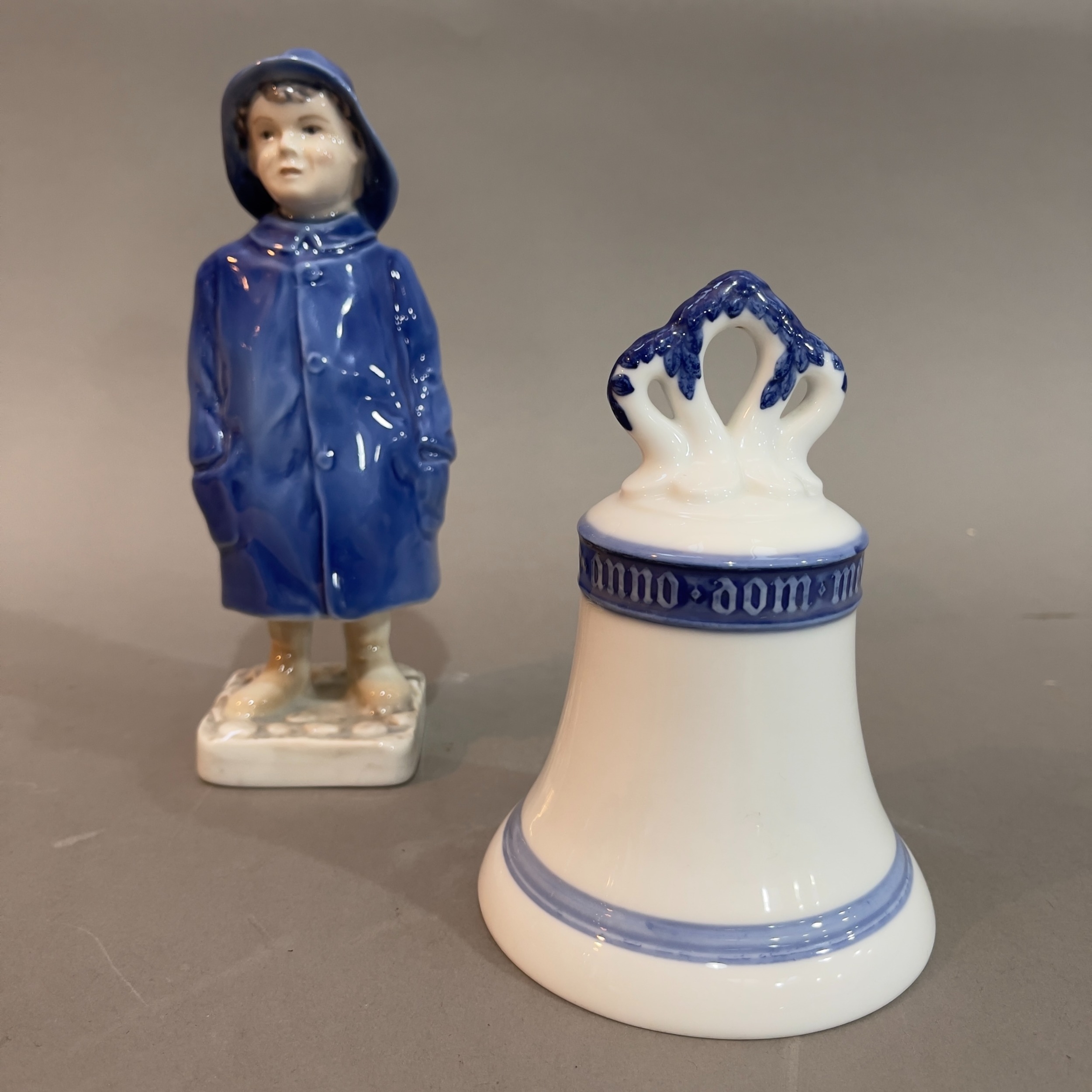 A Royal Copenhagen figure of a boy in a raincoat no.532 and a Royal Copenhagen bell, 13cm high