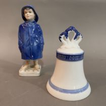 A Royal Copenhagen figure of a boy in a raincoat no.532 and a Royal Copenhagen bell, 13cm high