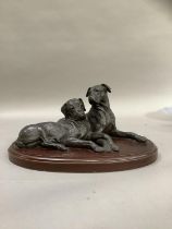 A bronze effect group of two boxer dogs on an oval plinth, 30cm wide x 15cm high