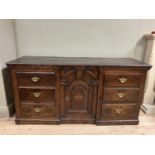 A oak dresser base having an inverted breakfront arched door cupboard inlaid with star paterae to