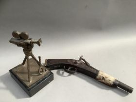 A flintlock pistol with animal pelt strap together with a bronze trophy