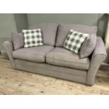 A two seater sofa upholstered in mushroom linen with loose cushions