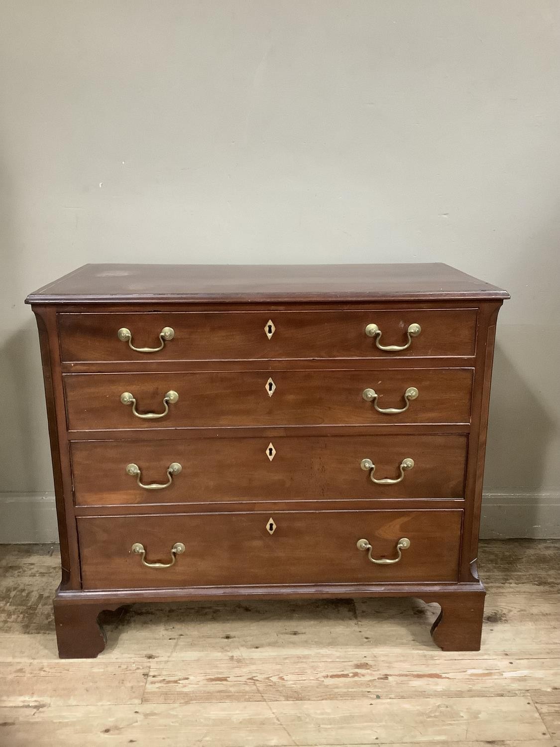 A mahogany and cross banded chest of four graduated drawers with brass swing handles and on shaped