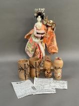 Two Japanese Kokeshi dolls, a bamboo mug and a beaker and a model of a Geisha girl in elaborate