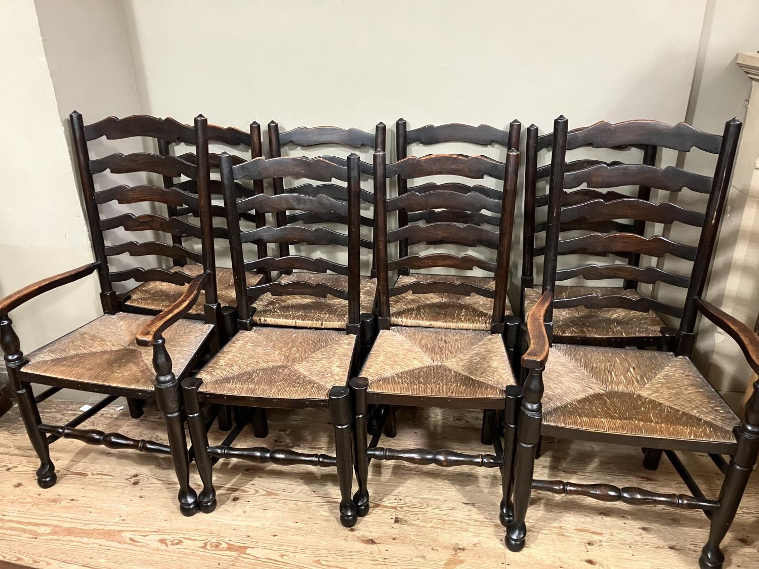 A set of eight early 20th century ladder back and rush seated dining chairs comprising two carvers