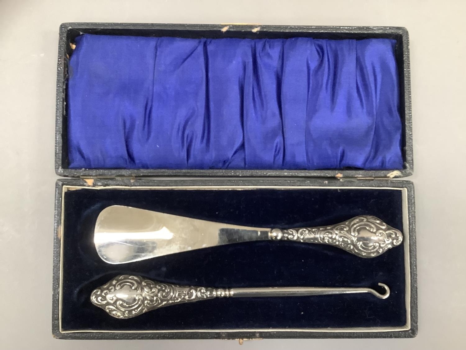 A George V silver topped shoe horn and button hook set, Chester 1912, foliate scroll chased with