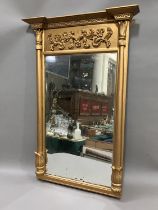A gilt mirror of early 19th century style having applied foliate scroll and inverted break front