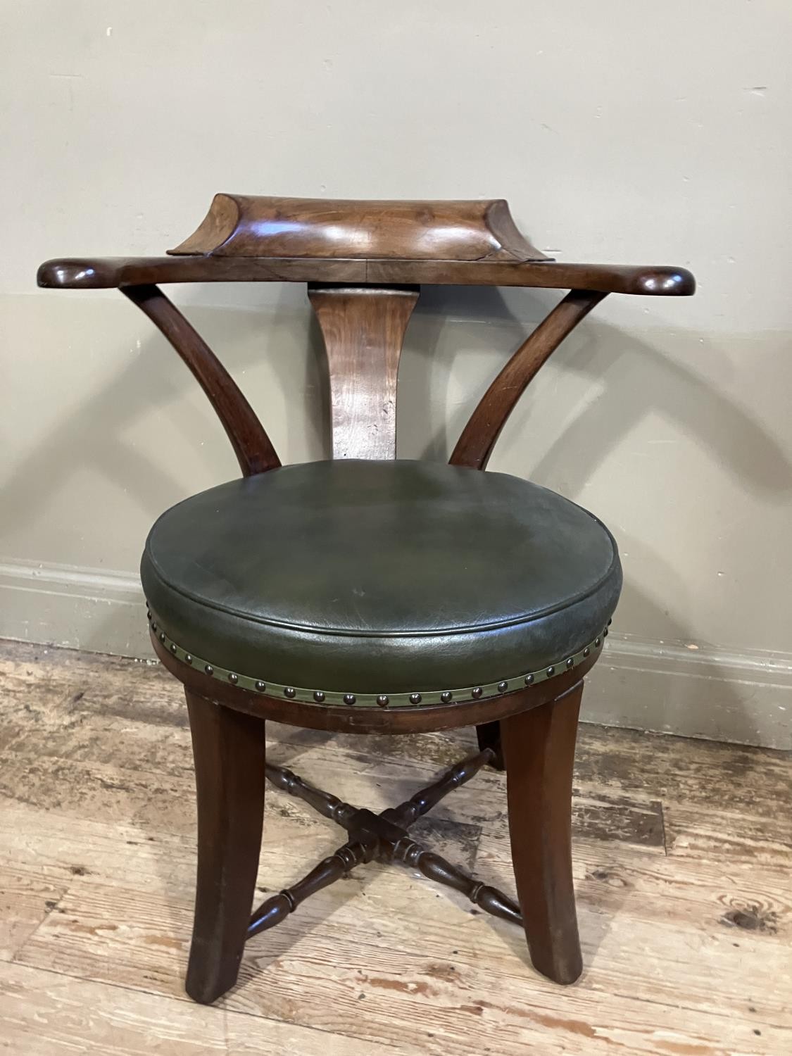 A Victorian walnut tub back chair with green leather upholstered revolving seat