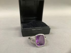 An amethyst and diamond ring in 9ct white gold, the cushion facetted amethyst collet set and flanked