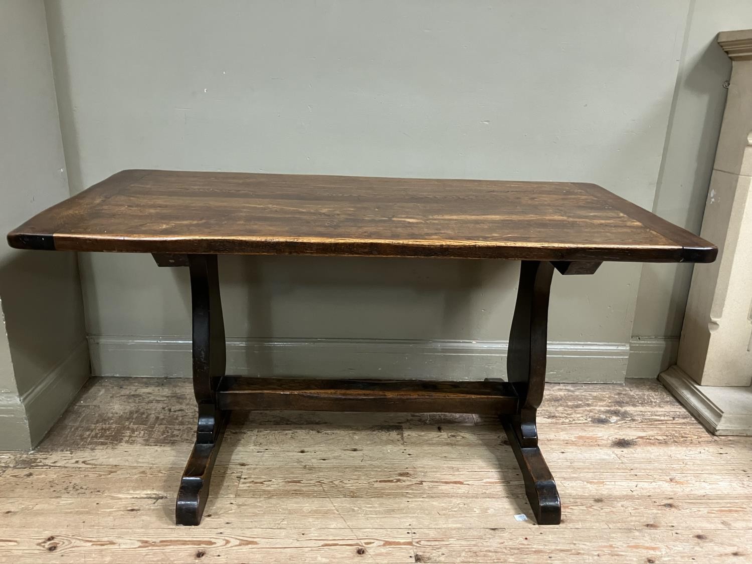 An oak refectory dining table on shaped standards and platform stretcher, 150cm x 74cm