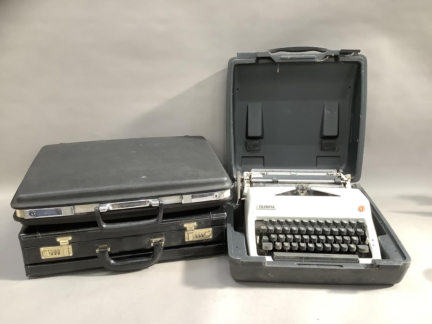 An Olympia portable typewriter in case, a lockable attache case, a Samsonite hard shell attache case