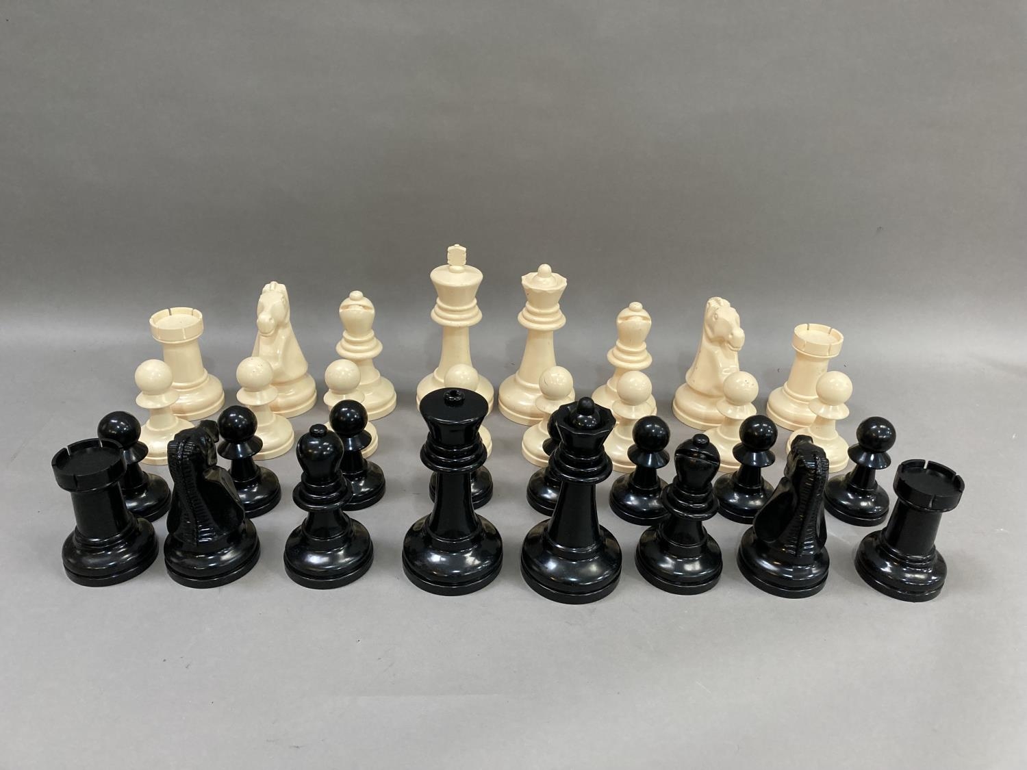 A outdoors chess set in cream and black plastic, the king measuring 21cm high