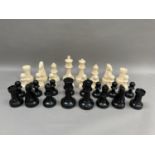 A outdoors chess set in cream and black plastic, the king measuring 21cm high