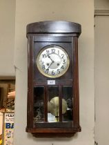 A 1930s dark stain wall clock with silvered dial and black Arabic numerals, eight day striking