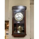 A 1930s dark stain wall clock with silvered dial and black Arabic numerals, eight day striking