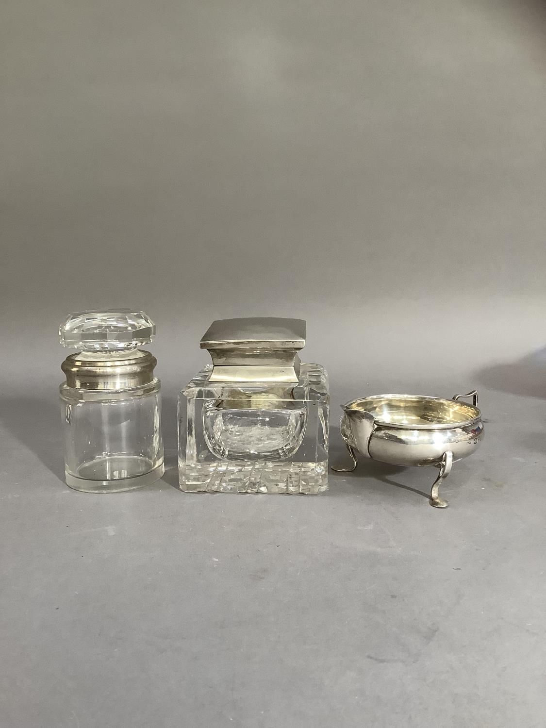 A silver cream jug, Chester 1922 together with a silver lidded glass inkwell of square outline