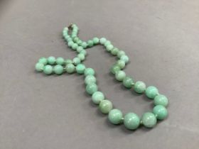 An early to mid 20th century jade necklace of graduated circular stained beads, approximate