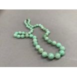 An early to mid 20th century jade necklace of graduated circular stained beads, approximate