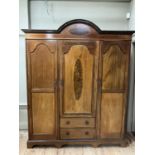 An Edwardian three door wardrobe of semi arched profile with moulded cornice, the middle door having